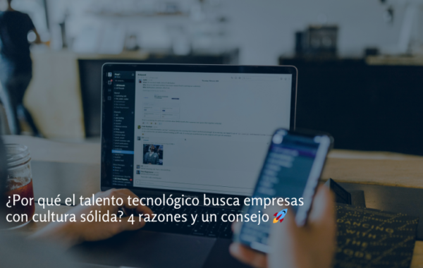 Profesional tecnológico usando una ordenador portátil y un smartphone en un espacio de trabajo moderno, representando la búsqueda de empresas con cultura organizacional sólida.